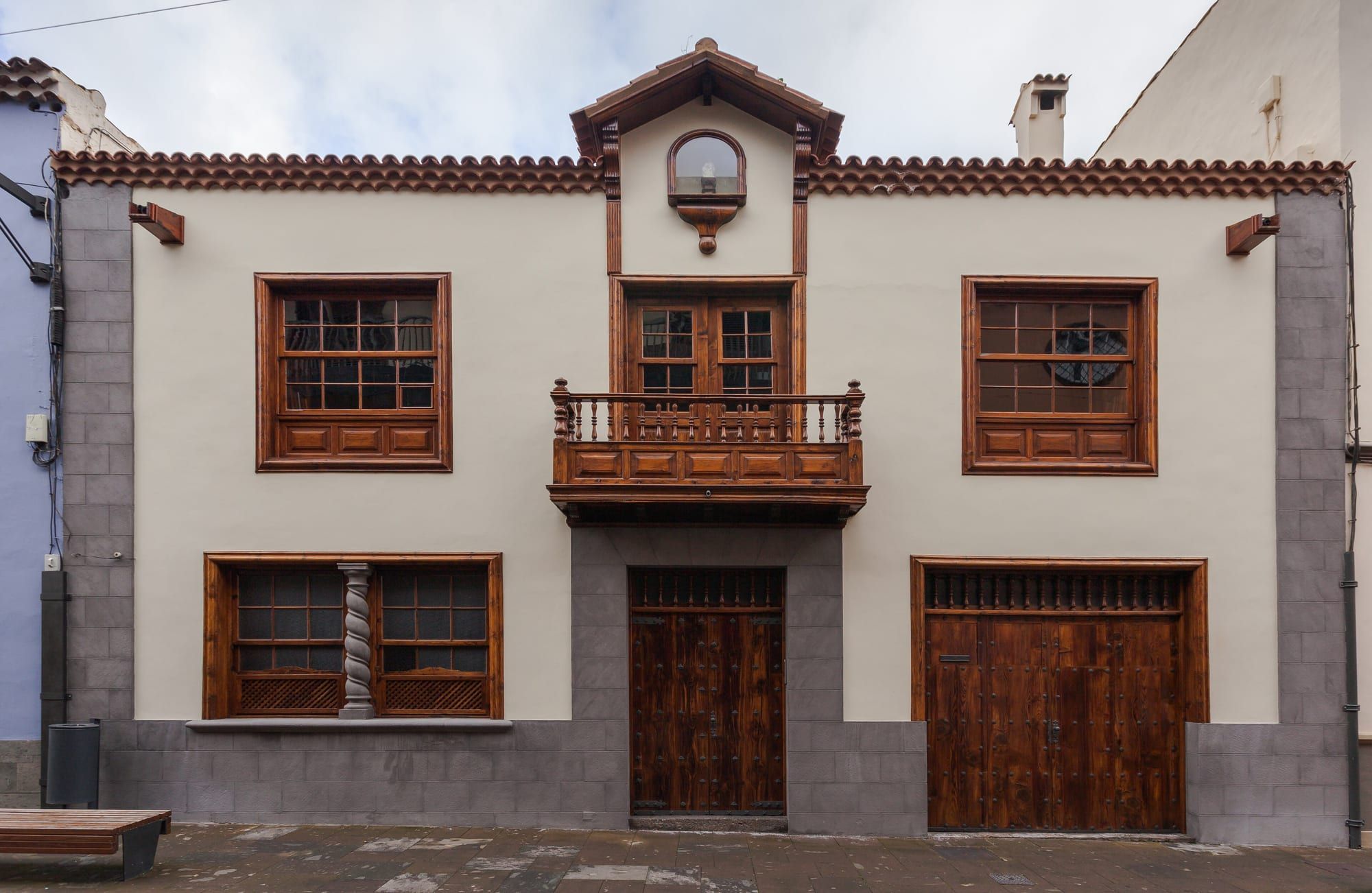 A traditional Canarian house at Calle San Agustín 6 in La Laguna, with dark wooden windows, a carved wooden balcony and stone-framed wooden doors